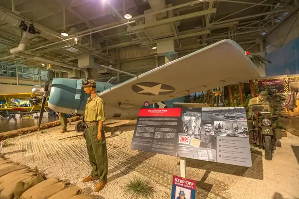 A museum exhibit featuring a military aircraft, informational display, and mannequin dressed in historical attire
