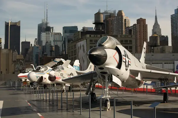 Military aircraft displayed at a museum deck with city skyscrapers in the background
