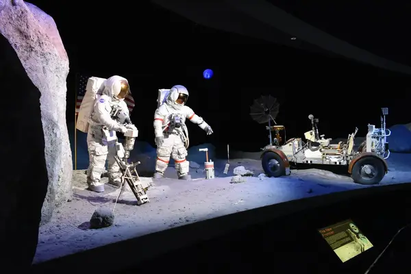 Museum exhibit of astronauts on a lunar surface with equipment and a rover