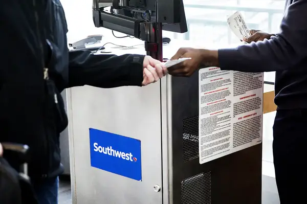 Passenger handing over a boarding pass to an agent at a Southwest Airlines boarding desk