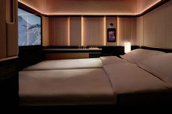 Modern double bed in a dimly lit luxury room with a screen displaying a snowy mountain view