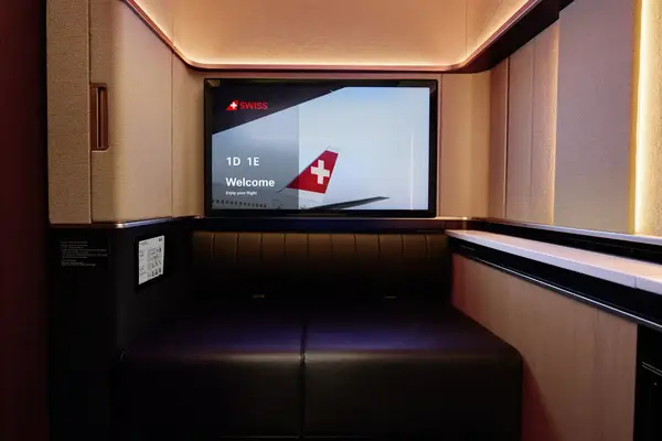 First class suite interior with a Swiss Airlines welcome screen and seating