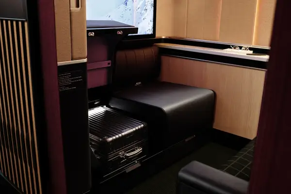 A private seating area in a train cabin with a luggage compartment visible