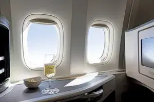 Business class airline seat with champagne glass and a television screen