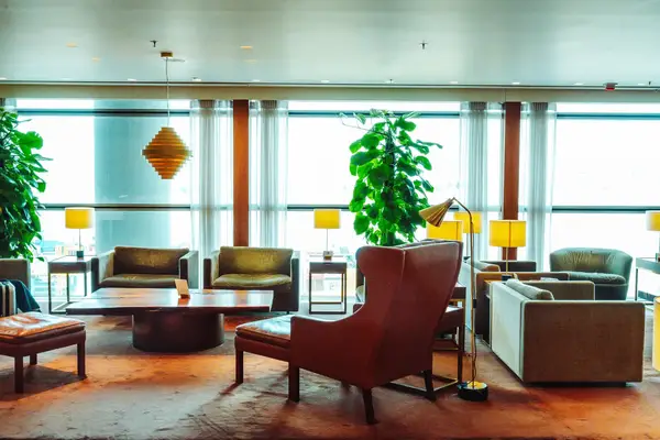 Lounge area with seating tables and potted plants near windows