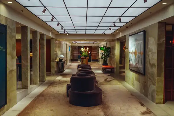 Lobby area with modern seating and artwork adorned with flowers and plants illuminated by a grid light ceiling