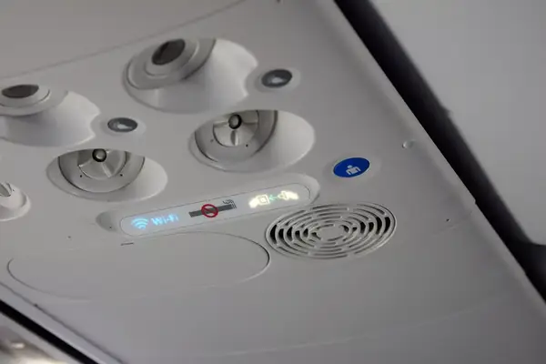 Overhead control panel on an airplane with ventilation, lighting, and passenger instruction icons