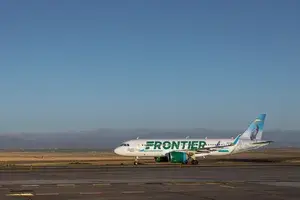 A Frontier Airlines airplane on an airplane tarmac 