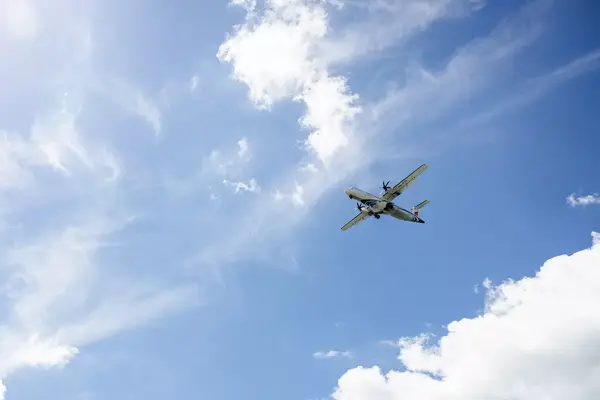 An airplane mid-flight against a background of a blue sky with clouds