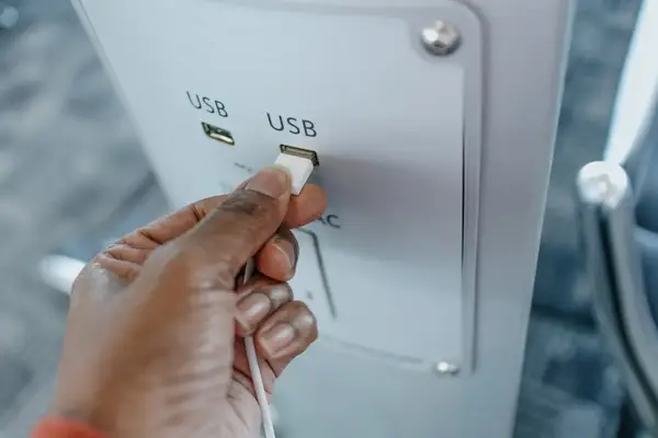 A hand plugging a USB cable into a public USB charging port