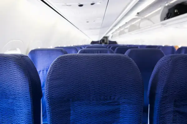 Airplane cabin with rows of empty blue seats