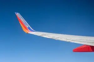 The wing of a Southwest Airlines plane is seen against a bright blue sky
