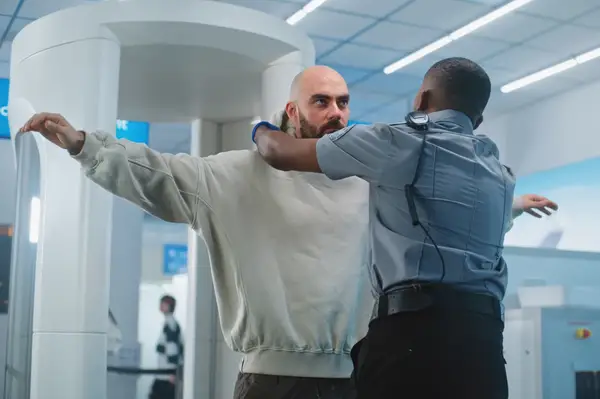 A TSA agent performs a security patdown on a traveler at a screening station in an airport