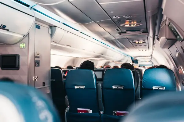 Interior view of an airplane cabin showing passenger seats and the aisle