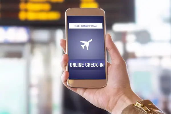 A hand holding a smartphone displaying an online flight check-in screen at an airport terminal