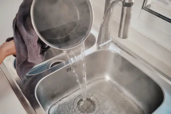 pouring boiling water to unclog the kitchen sink