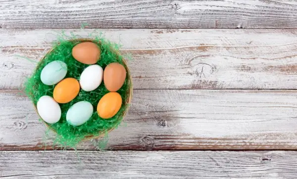 colorful real eggs on artificial green grass in basket for easter background