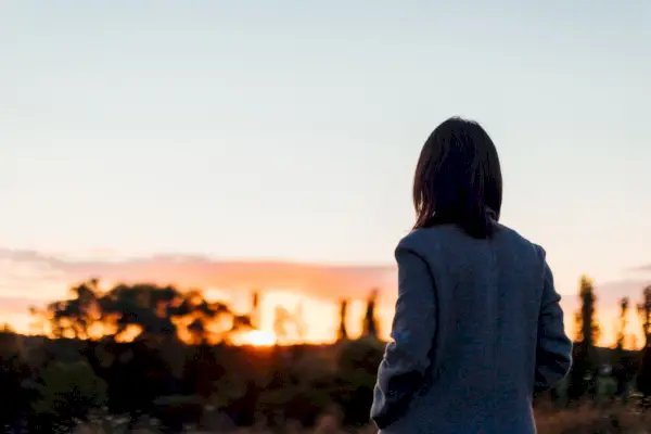 rear view of depressing young woman watching sunset at the park self care for mental wellbeing concept