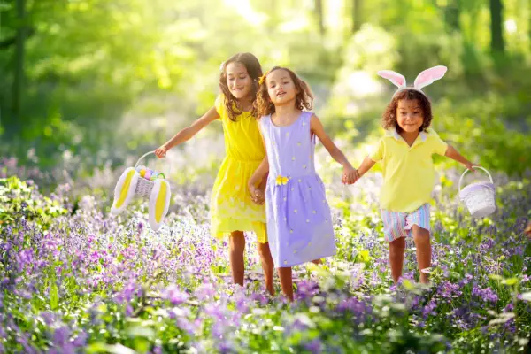 easter egg hunt group of kids searching for colorful eggs children wear bunny ears boy and girl with egg basket during spring holiday in sunny blooming park spring flower meadow