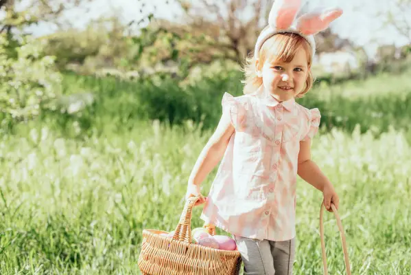 easter egg hunt girl child wearing bunny ears running to pick up egg in garden easter tradition baby with basket full of colorful eggs