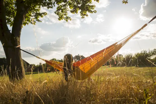 back view of woman with headphones lying in a hammock relaxing in nature