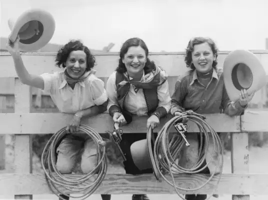 three cowgirls on a fence