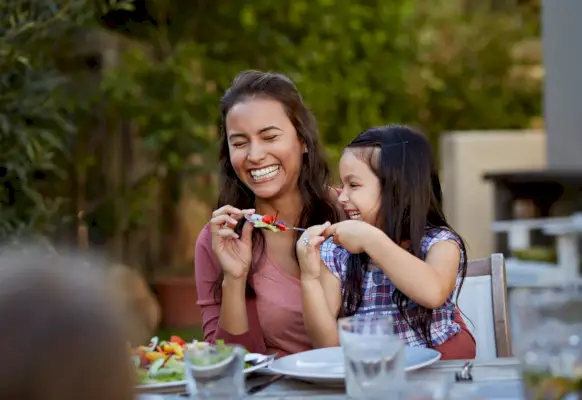 mom and daughter eating outside laughing