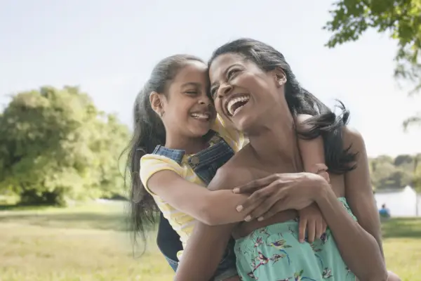 hispanic mother and daughter playing in park