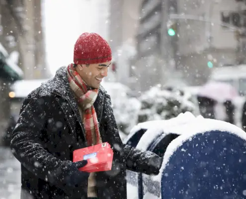 man mailing christmas cards in city