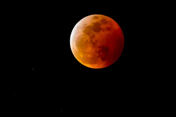 a blood moon, or full moon with a reddish shadow due to a total lunar eclipse, in the night sky