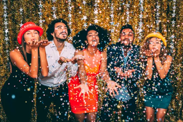 friends blowing confetti at a new years party
