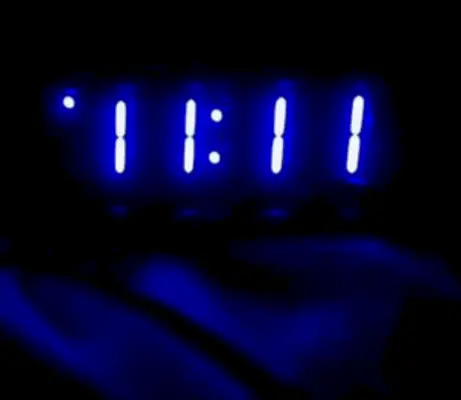 digital alarm clock in the dark with time in blue numbers reading 11 11