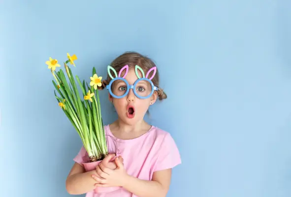 cute girl wearing bunny ears glasses and holding yellow daffodils