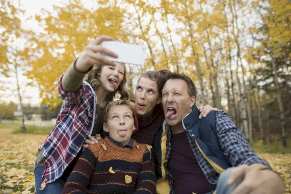 Silly family taking selfie making faces autumn park
