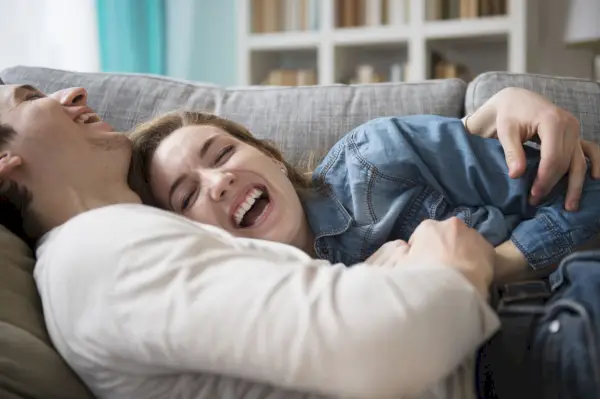 couple lying on a couch together laughing and cuddling