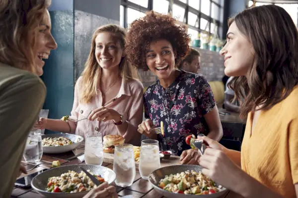 four young female friends meeting for drinks and food making a toast in restaurant