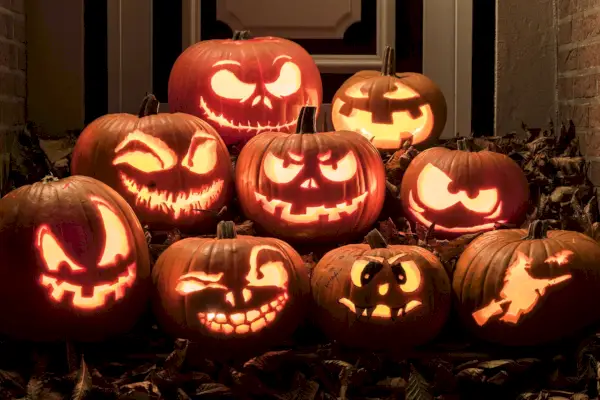 night shot of carved illuminated pumpkins on steps front of a house