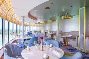 Sophisticated restaurant interior, ornate ceiling, with views outside through large windows, set tables with elegant decor