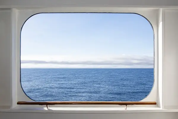 View of the ocean visible through a rectangular window with a wooden guardrail