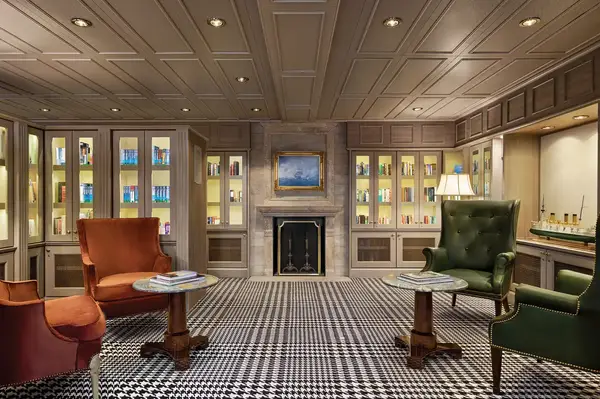 Interior of a library with seating, bookshelves, and a decorative fireplace