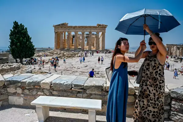 Two women shield themselves from harsh sun at the Acropolis