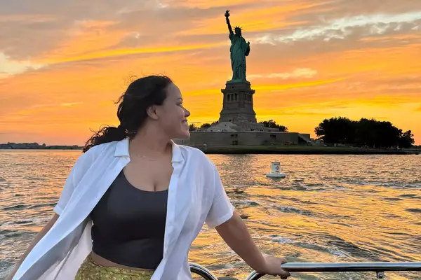 A woman on the Aman New York Yacht sailing past the Statue of Liberty 