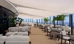 Rooftop terrace with tables, chairs, and large shade sails