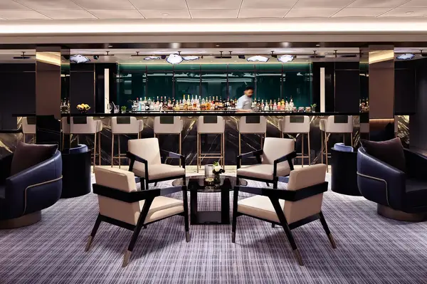 A stylish lounge area with modern chairs and a bar in the background, featuring a staff member behind the bar