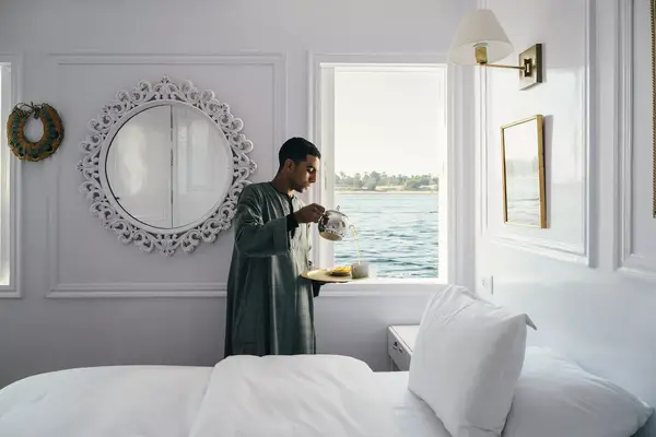 A man pours tea in a guest cabin on a boat