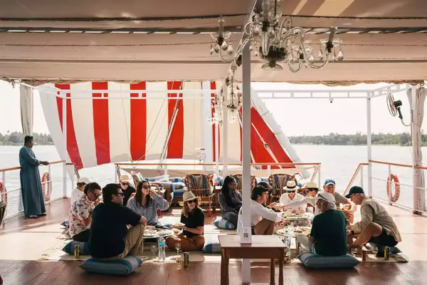 People sit on floor cushions while having lunch on board a sailing boat