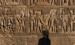 Silhouette of a woman looking at carvings in an Egyptian temple