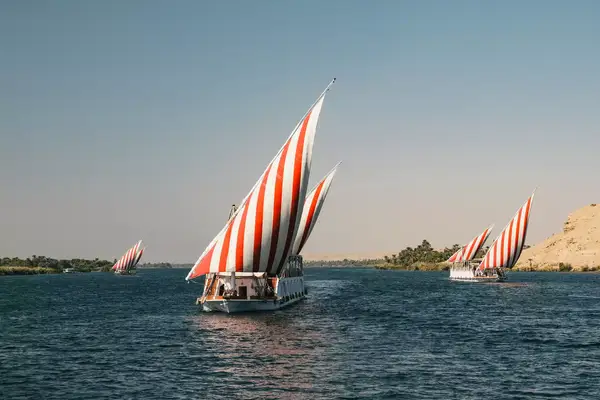 Red and white sailed traditional botas cruising the Nile