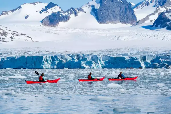 Kayakers kayaking through ice along glacier in Samarinbreen, Svalbard