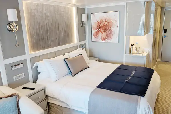 Luxury stateroom with a large bed lounge seating and modern decor onboard a cruise ship